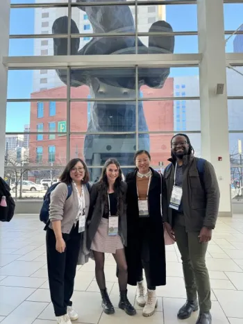 four people with a bear statue looking in from the outside