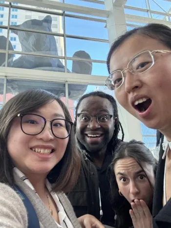 selfie of four people with bear statue in background